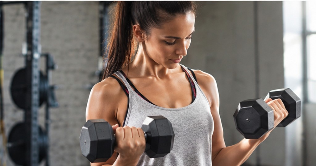 Woman lifting dumbbells during a bicep curl, focused and determined during a workout
