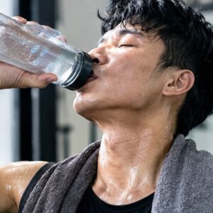 Man drinking water after an intense CrossFit workout, sweaty and recovering