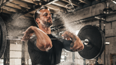 An athlete performing a barbell clean in a modern functional fitness box gym.