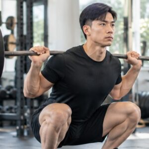 Man performing a barbell squat with proper form in a gym